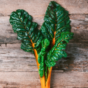 Swiss Chard Orange Glory leaves on a wooden table.